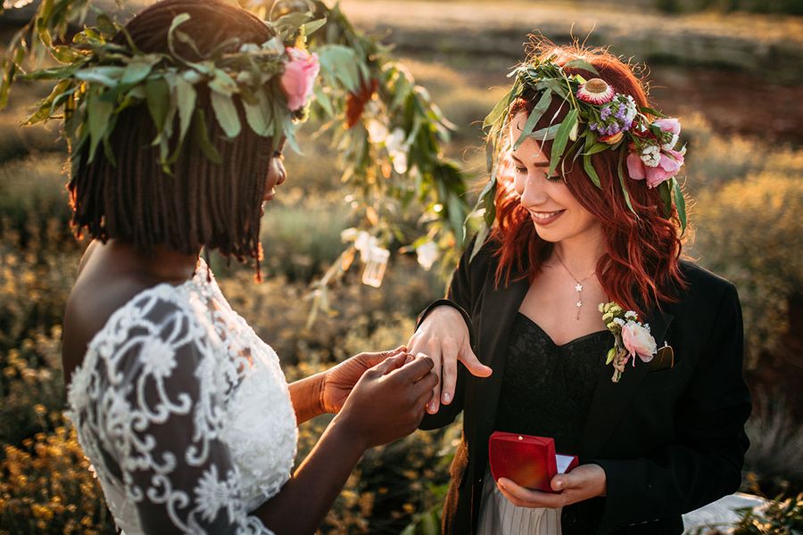 Dos novias intercambian anillos en su boda bohemia al aire libre, capturando un momento clave de la checklist de fotos de la ceremonia de boda.