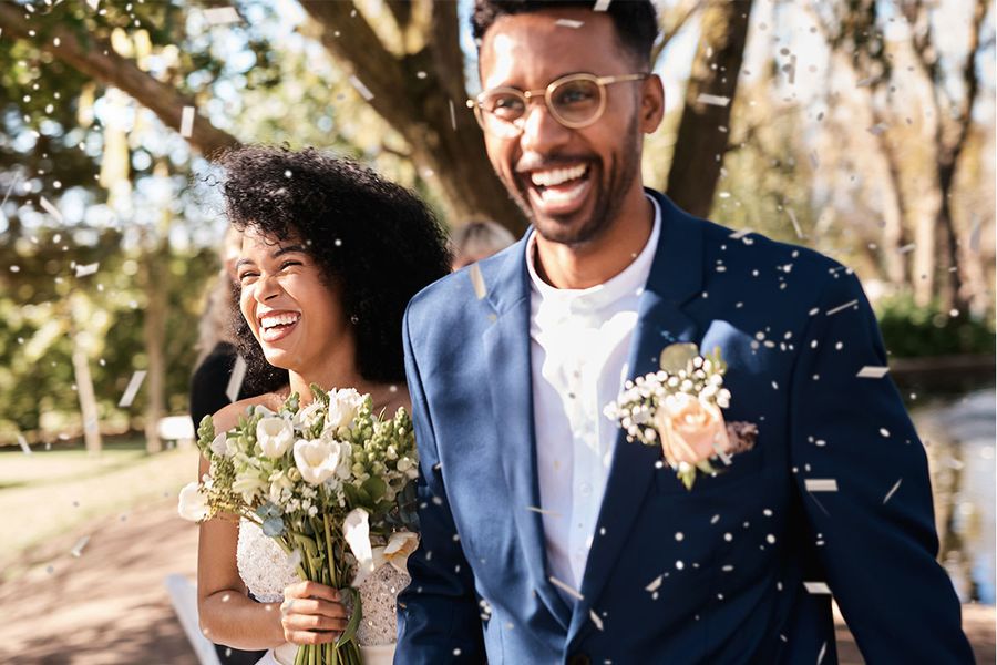 Una novia y un novio sonríen mientras caminan por el pasillo entre confeti, capturando un momento alegre de la checklist de fotos de retratos de boda.