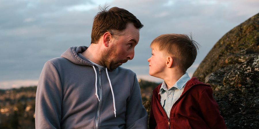 Un padre y su hijo haciendo muecas. Una divertida idea de regalo Hofmann para el Día del Padre.