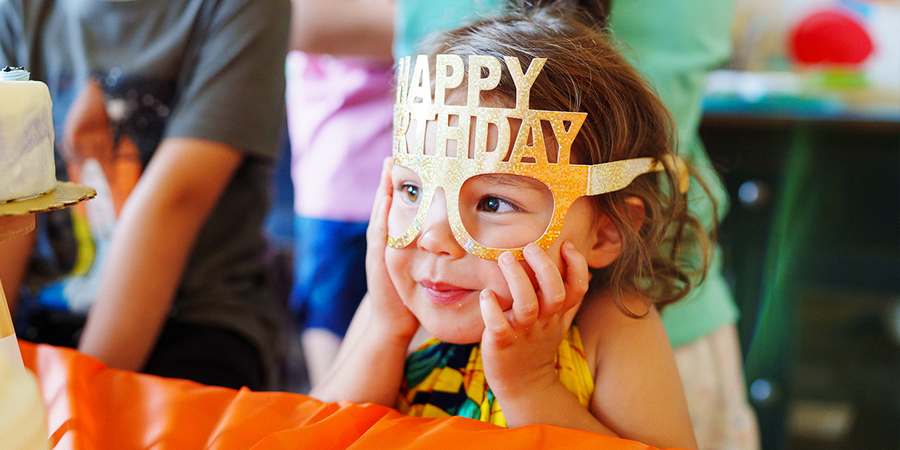 Una niña con gafas de fiesta de Feliz Cumpleaños, buscando los mejores regalos de cumpleaños e ideas de regalo de cumpleaños de Hofmann.