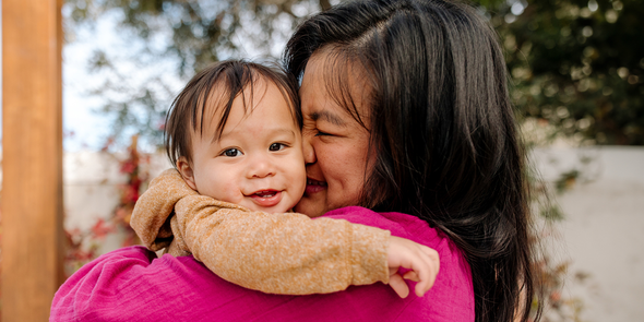 Una madre sonriente acariciando a su bebé; una idea de regalo Hofmann para el primer día de la madre de una mamá primeriza en 2026.
