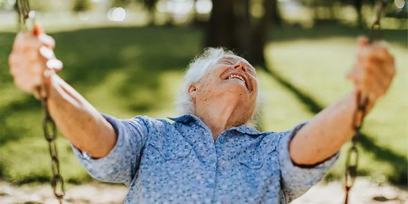 Un hombre mayor sonriendo en un columpio al aire libre en un bonito día de primavera, como inspiración para Hofmann y para capturar fotos de primavera llenas de sol y color.