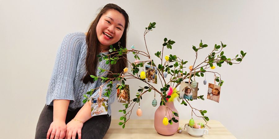 Vannie, especialista en marketing social de Hofmann, junto a un centro de mesa de Pascua DIY que consiste en un árbol en un jarrón con fotos impresas personalizadas colgando de las ramas.