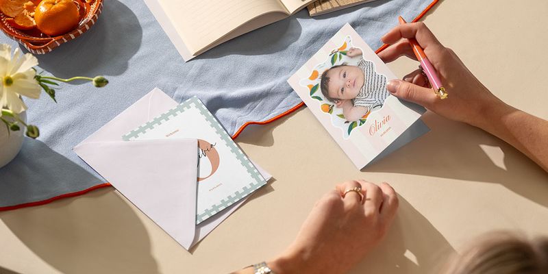 Una mujer escribiendo una felicitación de nacimiento para una niña, descubriendo ideas sobre qué escribir en una tarjeta de nacimiento de Hofmann.