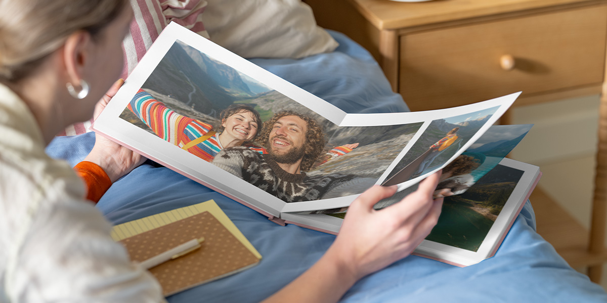 Inspiración para álbum de fotos Hofmann: una mujer mira un álbum de fotos abierto con una doble página de una pareja en un paisaje de montaña.