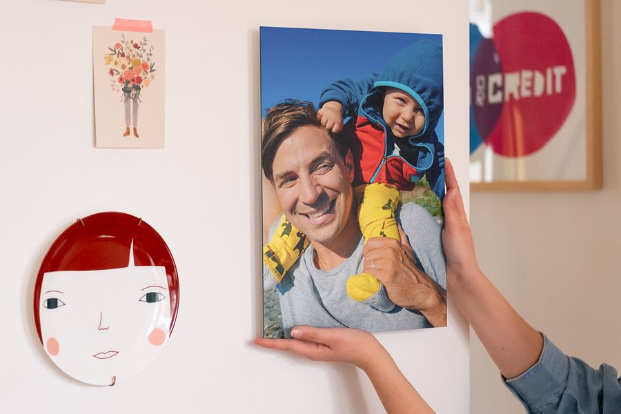 Alguien colgando un póster personalizado con fotos de un padre y un bebé en su pared.