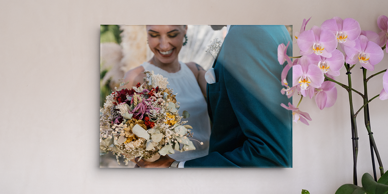 Un cuadro personalizado boda de Hofmann que muestra a una novia sonriente sosteniendo su ramo, colocado en una pared junto a una orquídea.