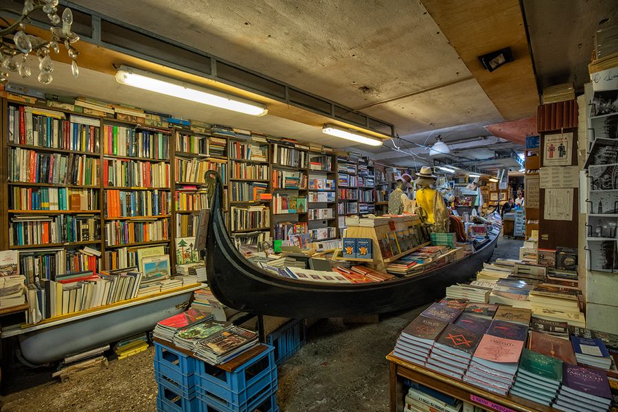 Libreria Acqua Alta en Venecia, Italia, con libros guardados en una góndola y bañeras para protegerlos de las mareas, una librería con encanto para un viaje literario con Hofmann.