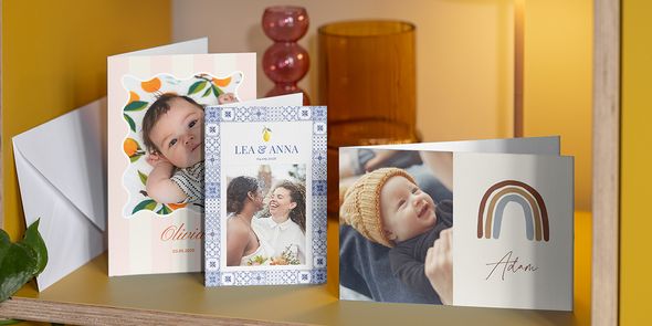 Una selección de tarjetas personalizadas en una estantería, incluyendo anuncios de nacimiento y una tarjeta personalizada de boda, mostrando lo fácil que es hacer tarjetas con fotos con Hofmann.