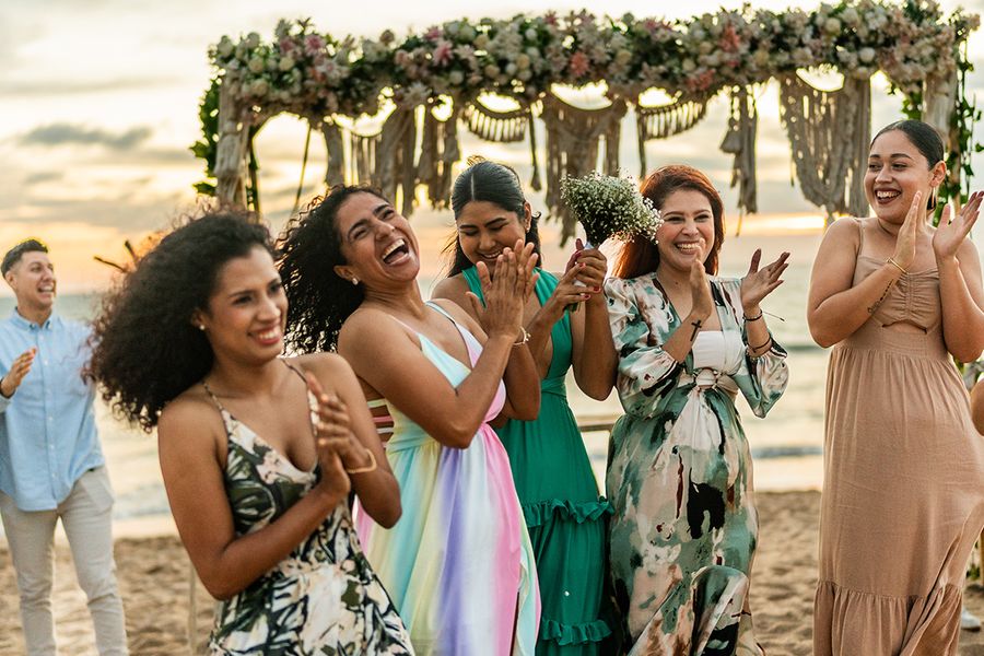 Una foto espontánea de una boda en la playa con invitados sonrientes, mostrando la estética de estilo paparazzi y las tendencias actuales en fotografía de bodas con Hofmann.