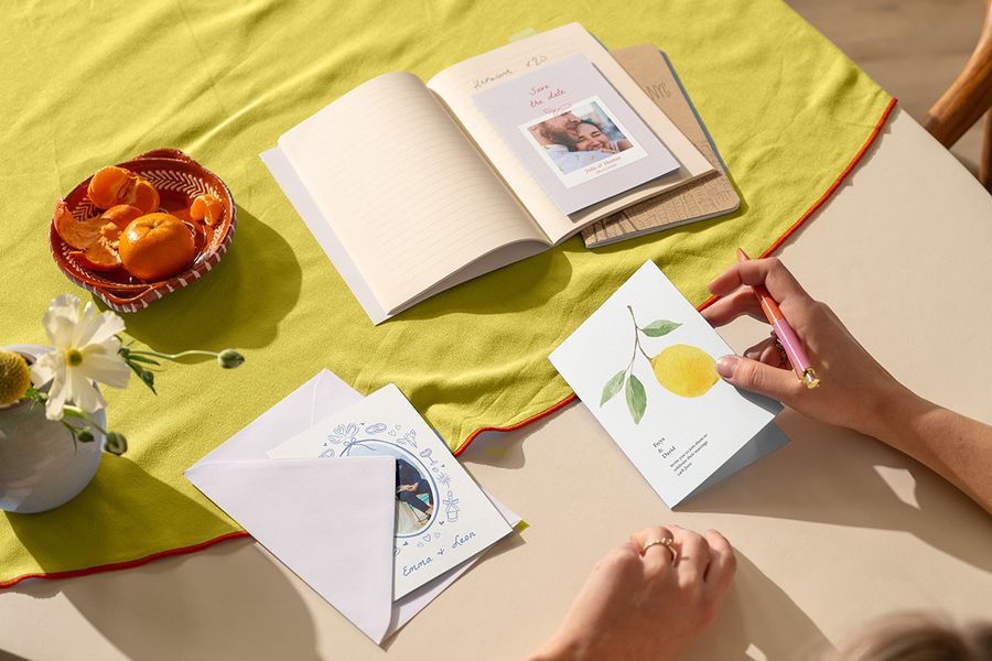 Invitaciones de boda personalizadas sobre un mantel de colores cítricos vibrantes, mostrando las tendencias de bodas para 2026 y cómo crear un tema de color con Hofmann.