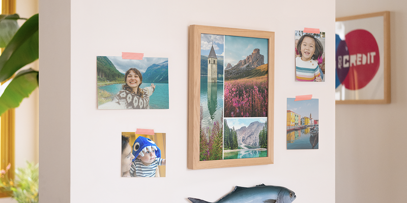 Impresiones de fotos de Hofmann en una pared del hogar, con un marco grande lleno de fotos de paisajes y cuatro fotos familiares individuales pegadas a la pared, como inspiración para imprimir fotos y pedir fotos online.