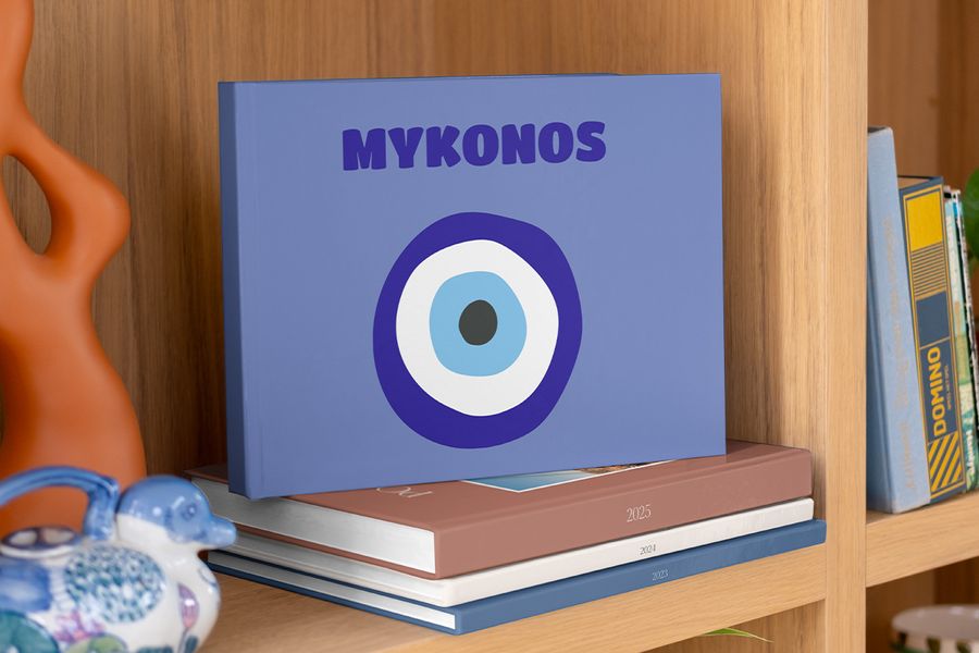 Un coffee table book de viajes de Hofmann con una llamativa portada azul y un diseño de ojo turco inspirado en Grecia, creado como una pieza decorativa para el salón.