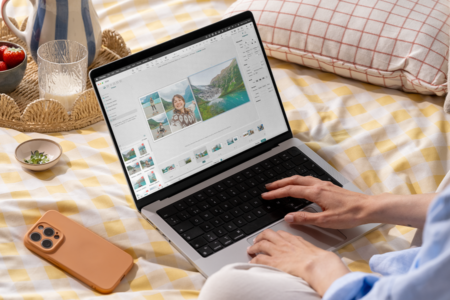 Una persona usa el editor de fotolibros de Hofmann en su portátil mientras está en la cama, como inspiración para un programa de fotolibros y un editor fácil de usar.