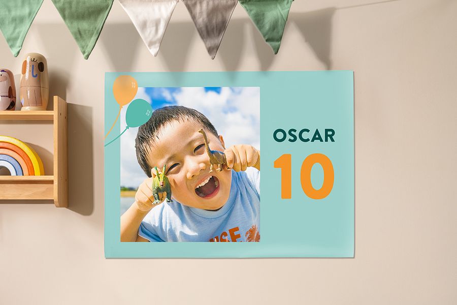 Un póster personalizado de Hofmann usado como decoración en una fiesta infantil, con un niño sujetando dinosaurios para celebrar su décimo cumpleaños, como inspiración para fiestas de cumpleaños para niños y decoración de fiestas.