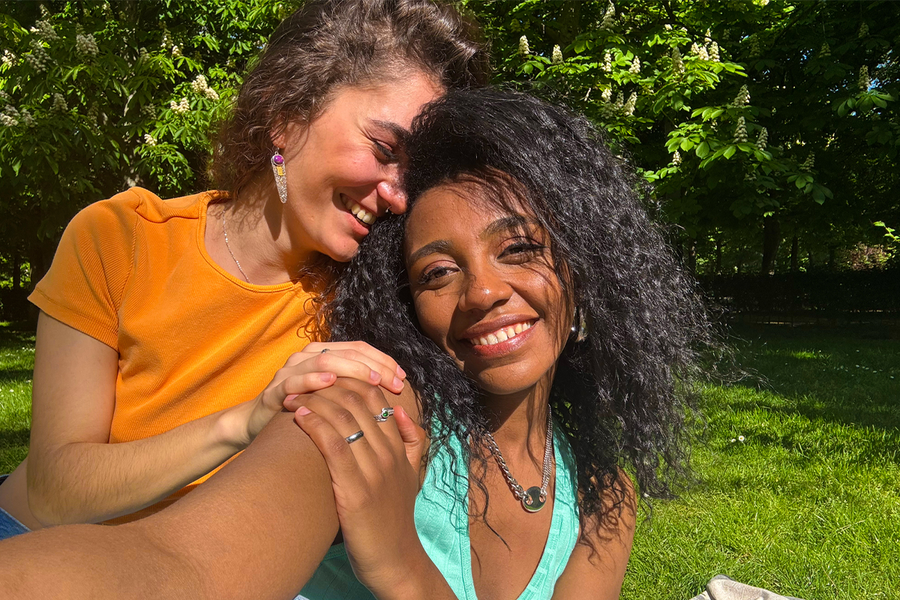 Dos mujeres sonríen mientras se hacen un selfi en un parque lleno de vegetación, mostrando cómo los colores intensos pueden hacer que las fotos al sol se vean más vivas y llenas de vida.