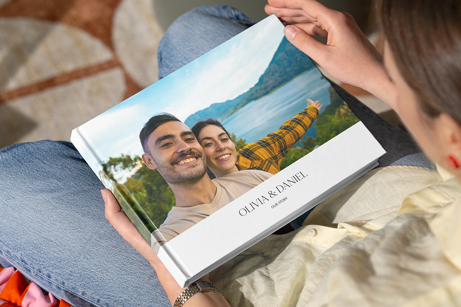 Un fotolibro personalizado de Hofmann con una pareja feliz en un lugar bonito en la portada, que ilustra la sorpresa de un fotolibro como idea romántica para pedir matrimonio.