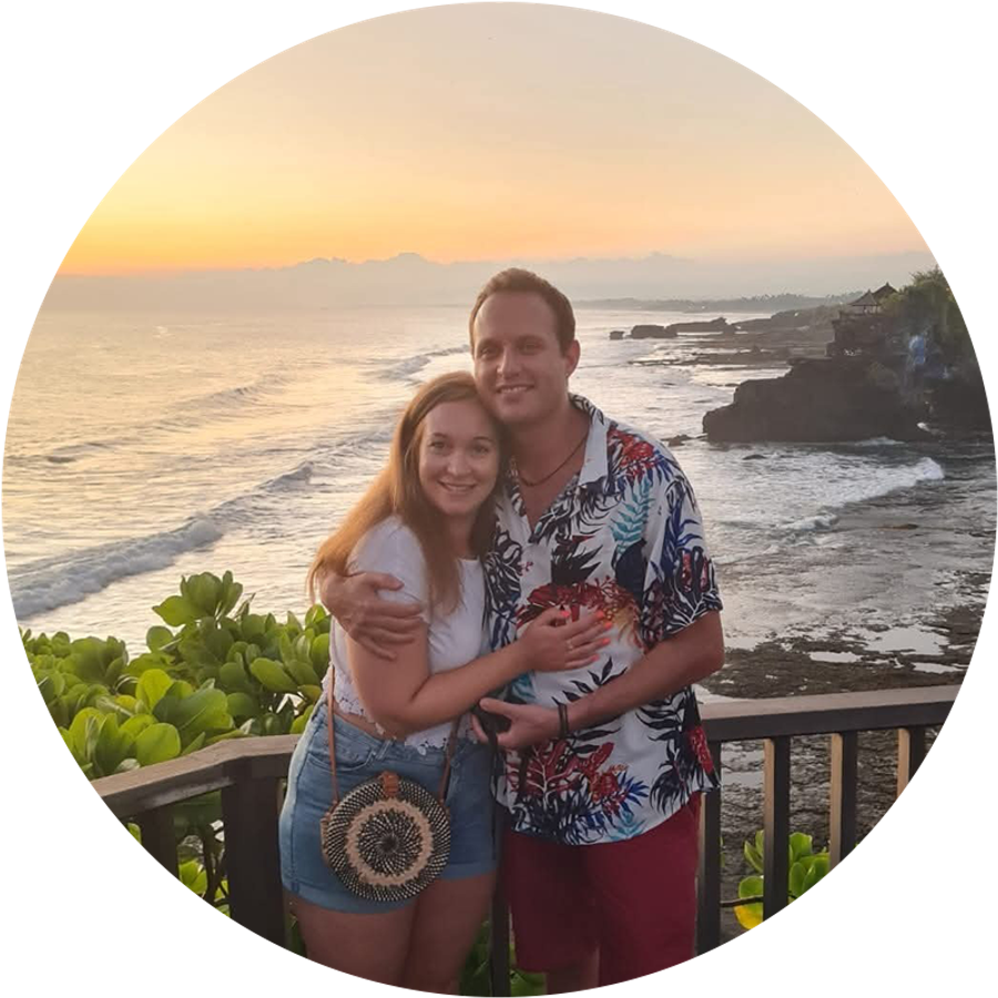 Claudia y su marido sonríen juntos frente a una preciosa puesta de sol en Bali, ilustrando su romántica historia de pedida de mano.