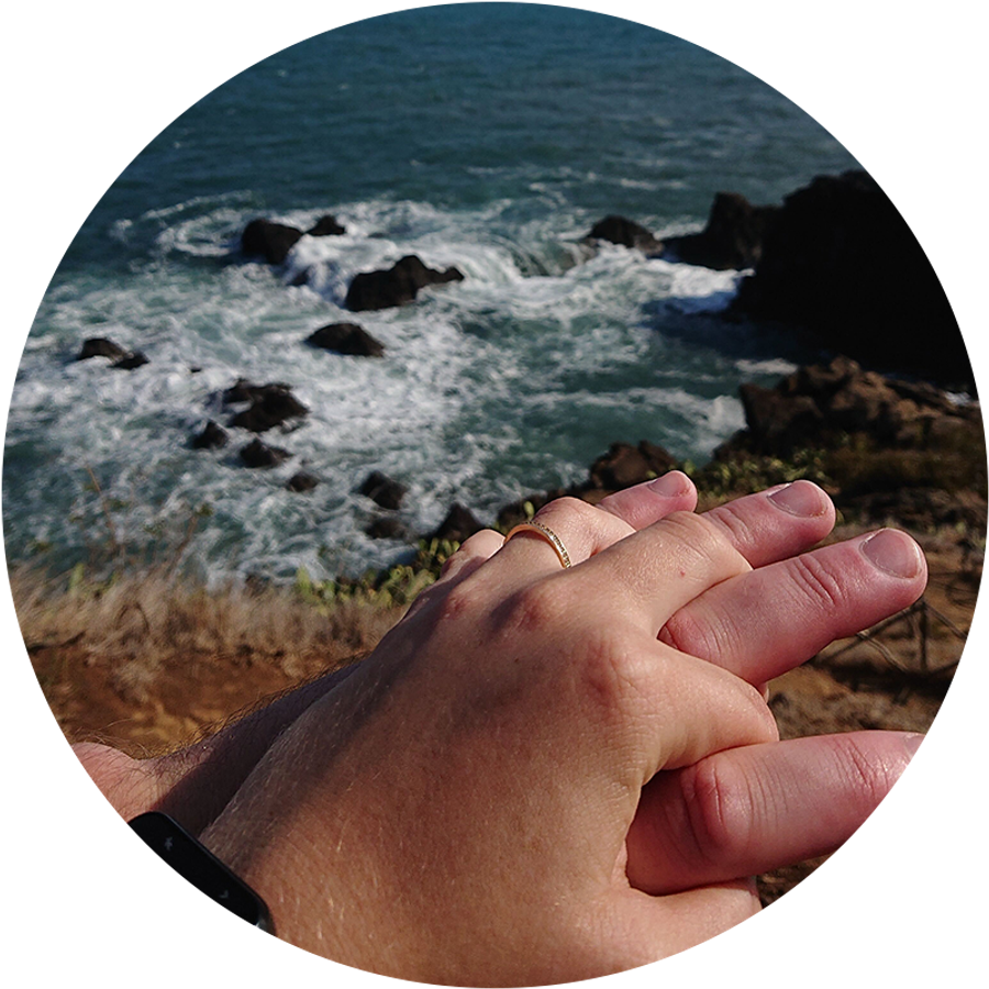 Dos manos entrelazadas junto al mar en Madeira, una de ellas con un anillo de compromiso, ilustran la romántica historia de pedida de mano de Kamilla durante sus vacaciones.