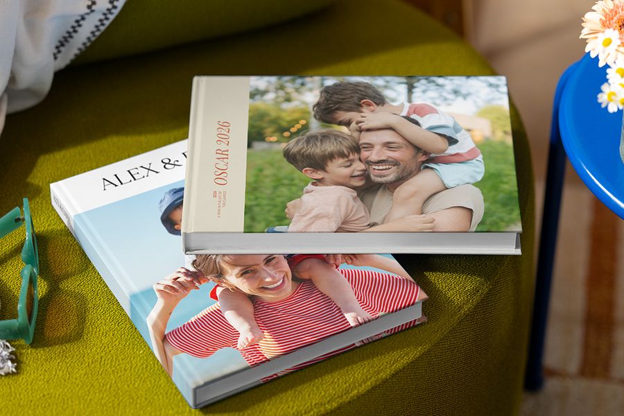 Dos álbumes de vacaciones de Hofmann diferentes con imágenes familiares en la portada, mostrando a padres, hijos, el nombre y el año, como ilustración de las mejores prácticas para crear un álbum de fotos de viaje personalizado.