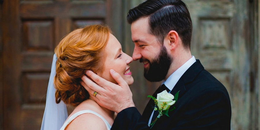 Una novia y un novio se sonríen mirándose a los ojos el día de su boda, con la mano del novio sobre la mejilla de la novia, como inspiración para ideas de fotos de boda de la checklist definitiva de fotos de boda.