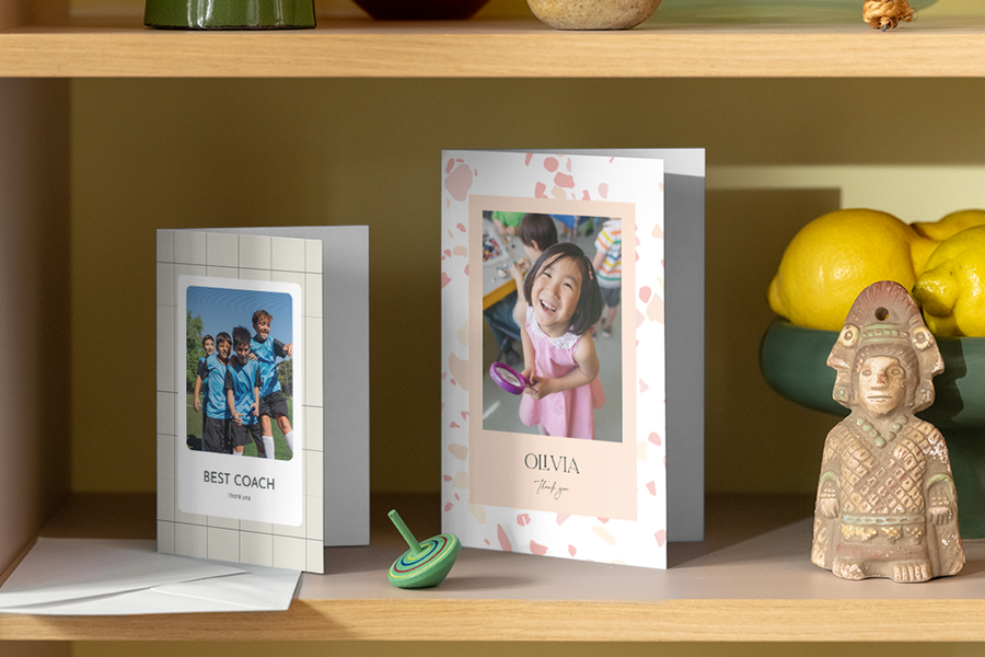 Dos tarjetas de agradecimiento personalizadas de Hofmann para profesores están colocadas en una estantería de casa.