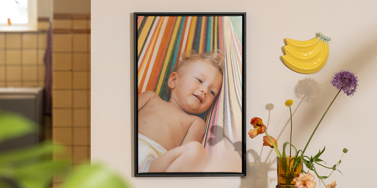 Un cuadro personalizado de Hofmann con la foto de un bebé junto a flores y decoración de frutas, como inspiración para la decoracion casa verano.