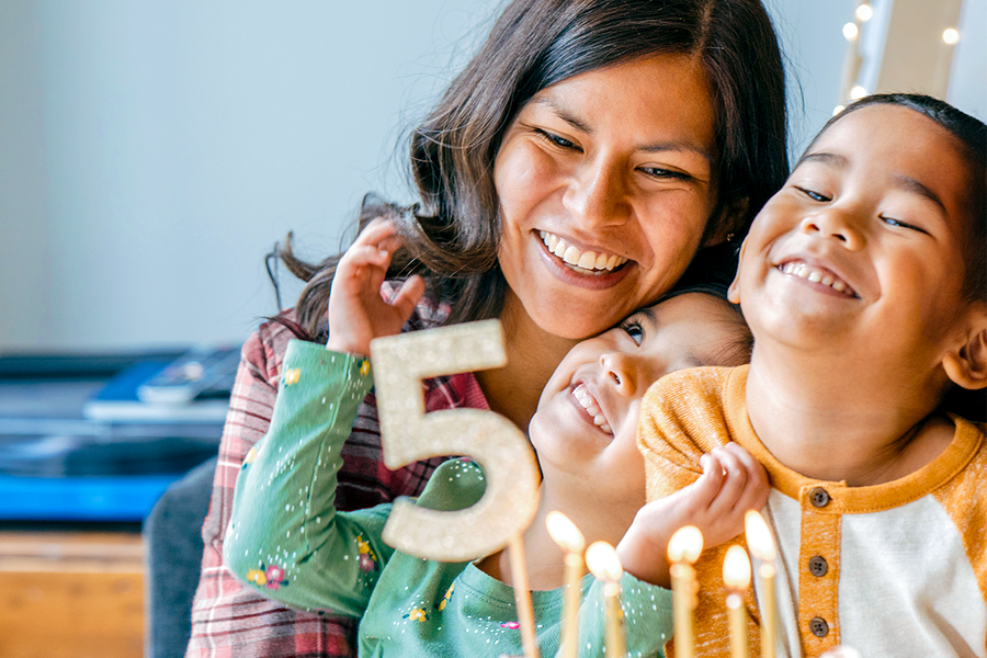 Una madre y sus dos hijos sonriendo junto a una tarta de 5º cumpleaños, una idea perfecta de regalo cumpleaños madre de Hofmann.