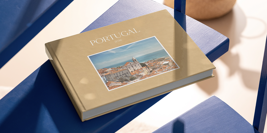 Un fotolibro familiar personalizado de Hofmann con la etiqueta Portugal 2026 está sobre una mesa, guardando recuerdos de viajes en familia y una bonita forma de recordar las vacaciones.