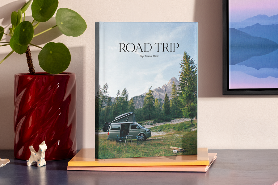 Un gran álbum de fotos en formato vertical muestra una foto de una autocaravana en un paisaje montañoso similar a un parque nacional, ilustrando las ideas de título para álbumes de fotos de viajes por carretera de Hofmann.