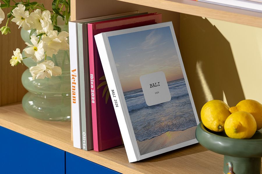 El nuevo álbum de fotos Modern Travelogue de Hofmann está sobre una estantería, mostrando diseños limpios y una tipografía elegante inspirados en revistas de viajes y libros de mesa de centro.