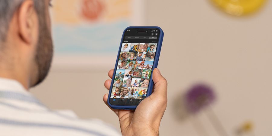 Un hombre sostiene su móvil y desliza el dedo por su carrete de fotos, ilustrando la guía de Hofmann para gestionar el exceso de fotos y organizar la galería.