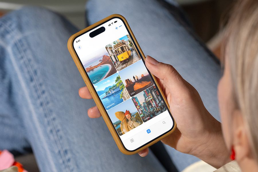 Una persona mira carpetas de fotos en su móvil con nombres de destinos vacacionales como 