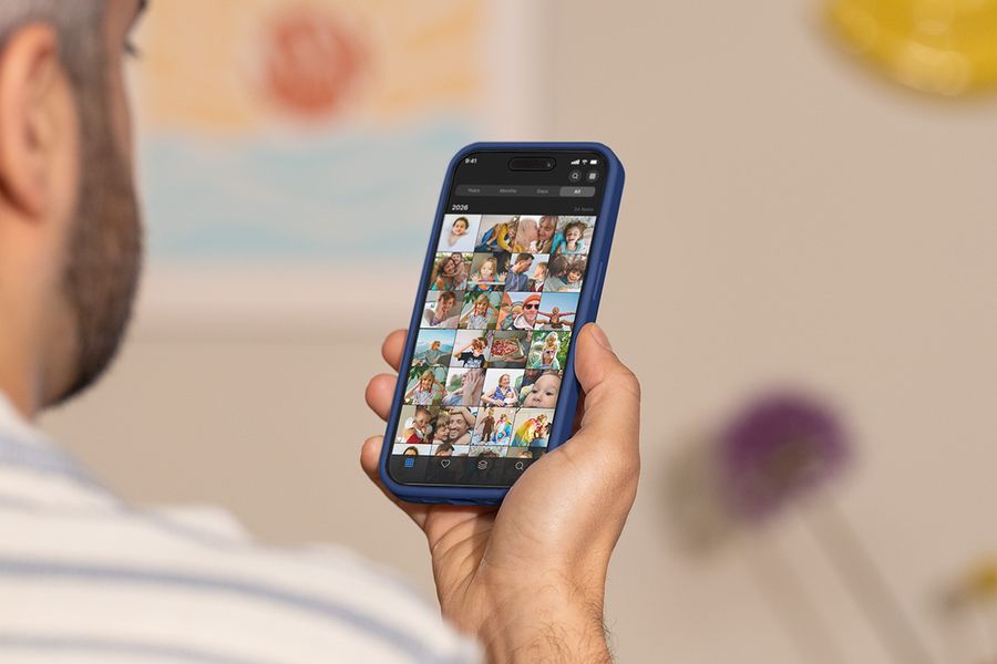 Un hombre sostiene su móvil y desliza el dedo por su carrete de fotos, ilustrando la guía de Hofmann sobre las mejores herramientas para organizar fotos.