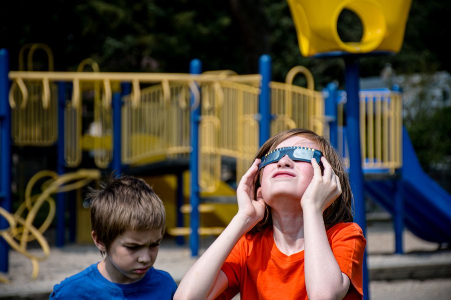 Un niño mira hacia arriba al eclipse solar con gafas de protección homologadas, ilustrando la advertencia de Hofmann sobre la importancia de usar gafas de eclipse certificadas para verlo de forma segura.