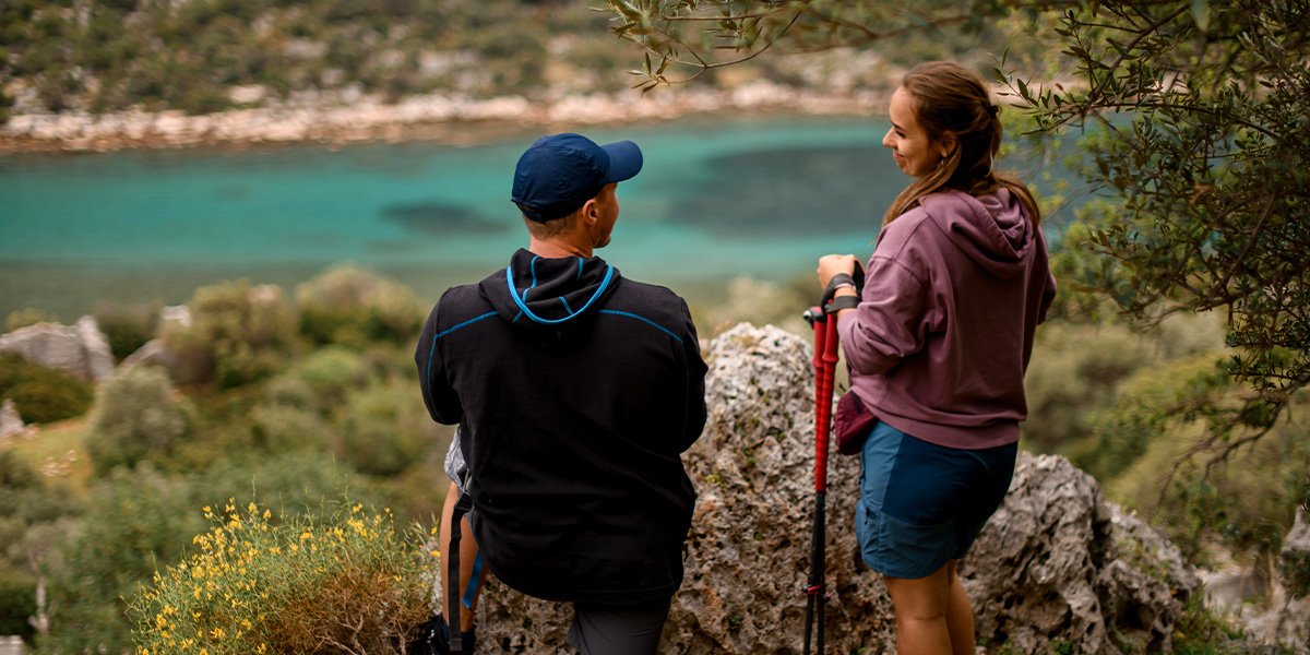 Una pareja se encuentra en un hermoso parque nacional mirando un lago azul, capturando la belleza natural que aparece en la guía de Hofmann sobre los parques nacionales más bonitos de Europa.