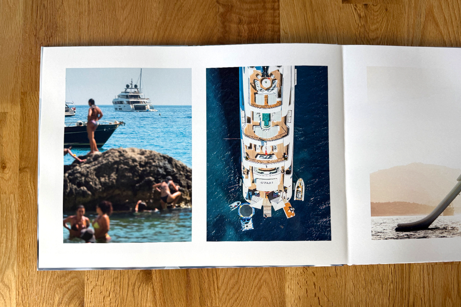Una doble página abierta del álbum de fotos de Charl van Rooy muestra escenas de vacaciones en la playa, con gente relajándose junto al mar y un yate, ilustrando el flujo visual de su portafolio fotográfico.