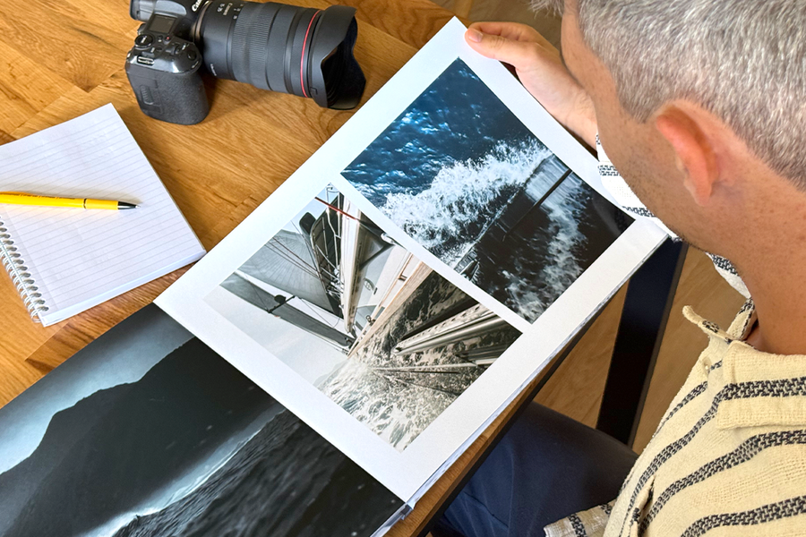 El fotógrafo Charl van Rooy mira su portafolio, con su cámara y una libreta sobre la mesa a su lado, ilustrando los consejos de Hofmann para elegir las mejores plantillas y diseños para un portafolio fotográfico.