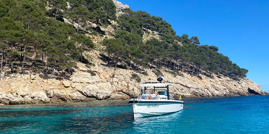 Gemma, redactora de Hofmann, está sentada en un barco frente a la costa de Ibiza, presentando sus destinos favoritos para viajar en septiembre por Europa.