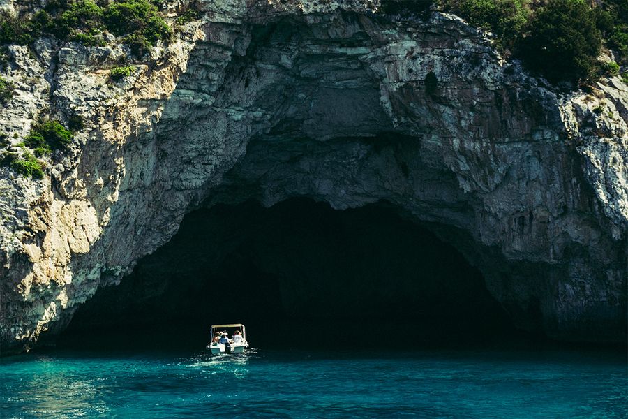 Un barco entra en unas cuevas marinas en Corfú, capturando el ritmo tranquilo y la belleza de unas vacaciones de septiembre en una isla griega.