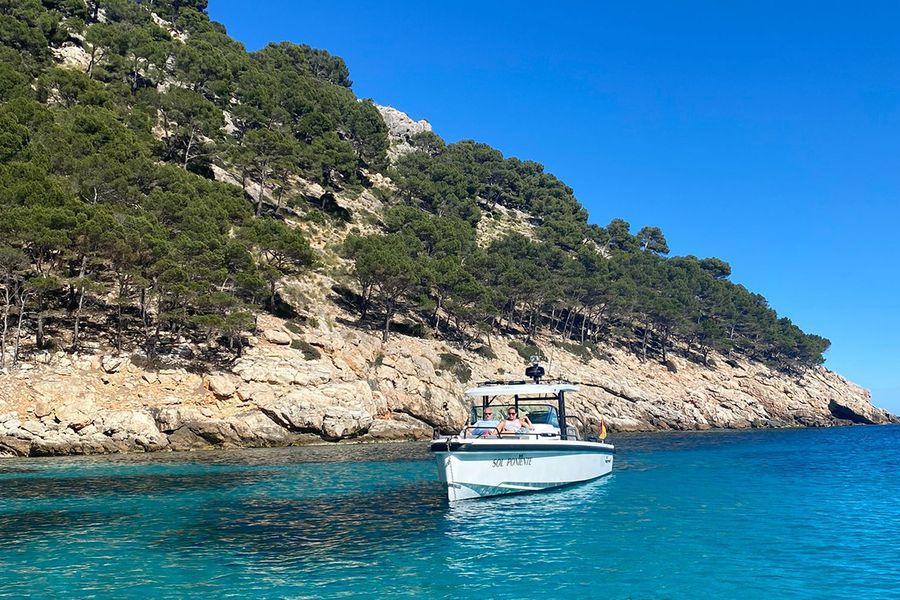 Una pareja está en un barco junto a una hermosa costa escarpada en Ibiza, capturando el lado más tranquilo y relajado de unas vacaciones de septiembre en la isla.