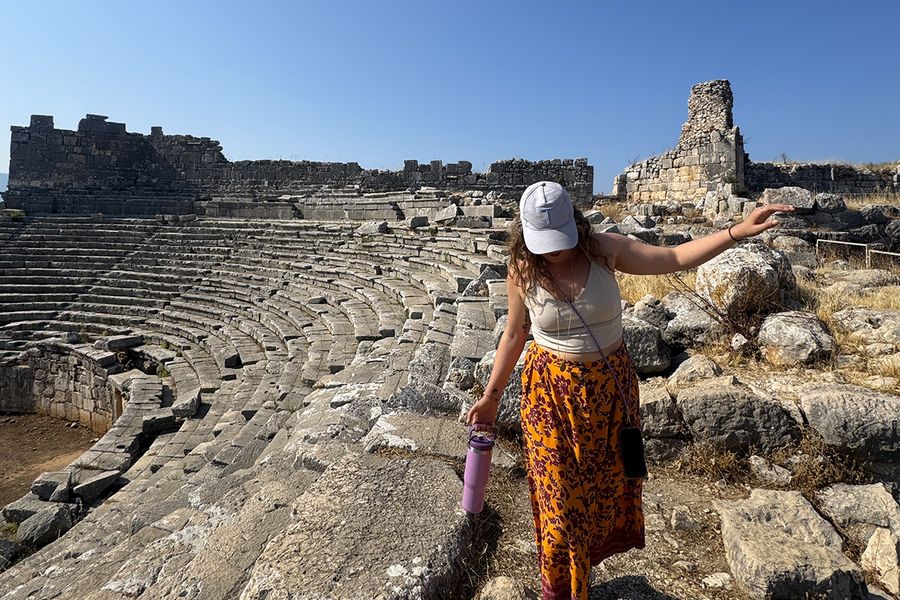Gemma, redactora de Hofmann, camina entre las rocas de un anfiteatro en Kalkan, Turquía, ilustrando cómo elegir el destino adecuado para las vacaciones de septiembre.