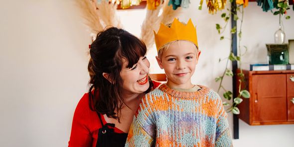 Un niño sonriente lleva una corona de cumpleaños mientras una mujer mayor le sonríe, ilustrando la checklist definitiva de Hofmann para la sesión de fotos de cumpleaños.