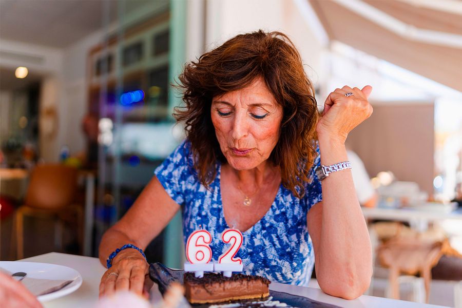Una mujer sopla las velas que marcan '62' en su tarta de cumpleaños, ilustrando el consejo de Hofmann de capturar el momento exacto en que se apagan las velas.