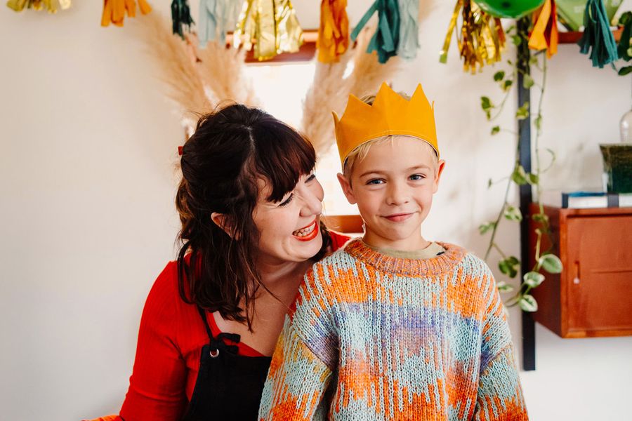 Un niño sonriente lleva una corona de cumpleaños mientras una mujer mayor le sonríe, ilustrando la checklist definitiva de Hofmann para la sesión de fotos de cumpleaños.