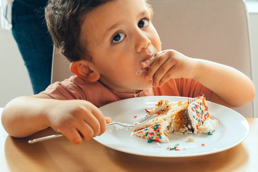 Un niño pequeño come tarta de cumpleaños, ilustrando la checklist fotográfica de Hofmann para captar los mejores momentos de una fiesta de cumpleaños infantil.