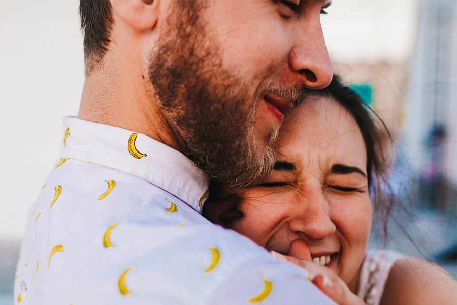 Una pareja se abraza, con la mujer sonriendo y los ojos cerrados, ilustrando las ideas de Hofmann sobre qué escribir en una tarjeta de aniversario de bodas.