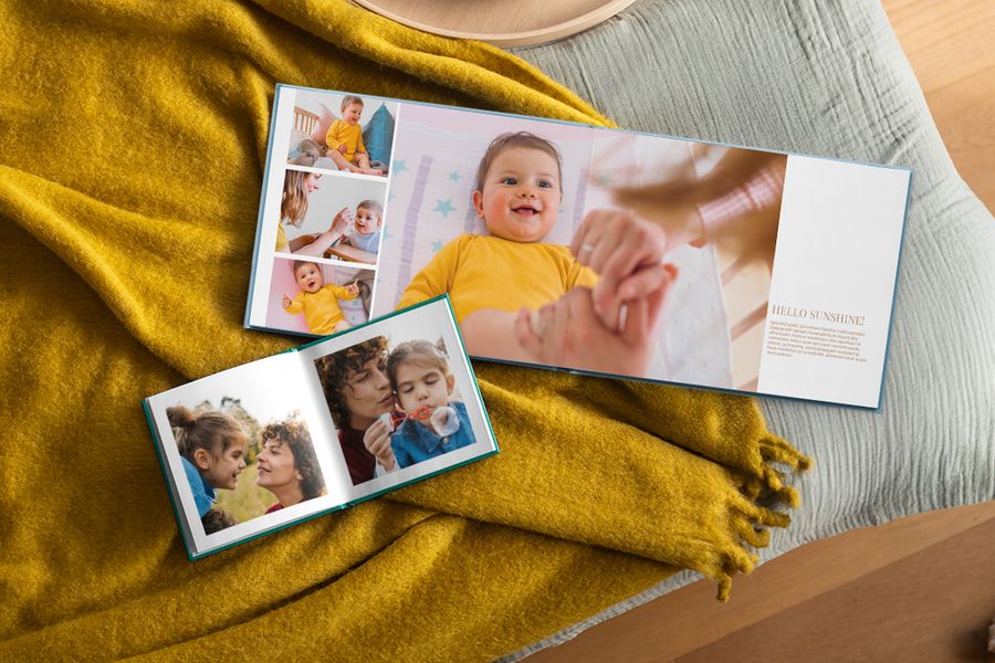 Dos álbumes de fotos personalizados abiertos con fotos familiares descansan sobre una manta amarillo mostaza, ilustrando cómo los álbumes de fotos de Hofmann encajan en un hogar hygge.