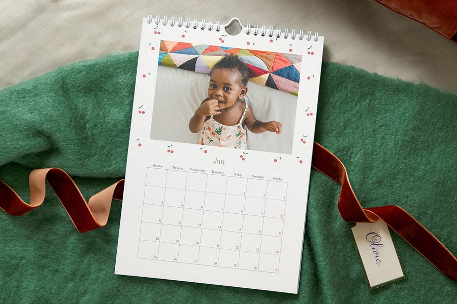 Calendario de fotos personalizado con una foto de un bebé con un vestido de verano, para ilustrar las ideas de Hofmann para crear un calendario personalizado para la primera Navidad del bebé.