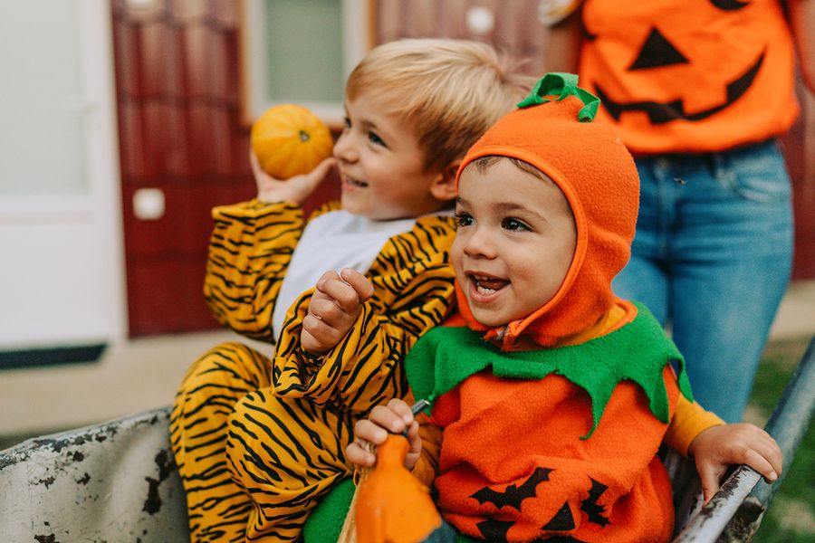 Dos niños disfrazados de Halloween, uno de calabaza y otro de tigre, ilustrando las frases tiernas de Halloween para Instagram de Hofmann.